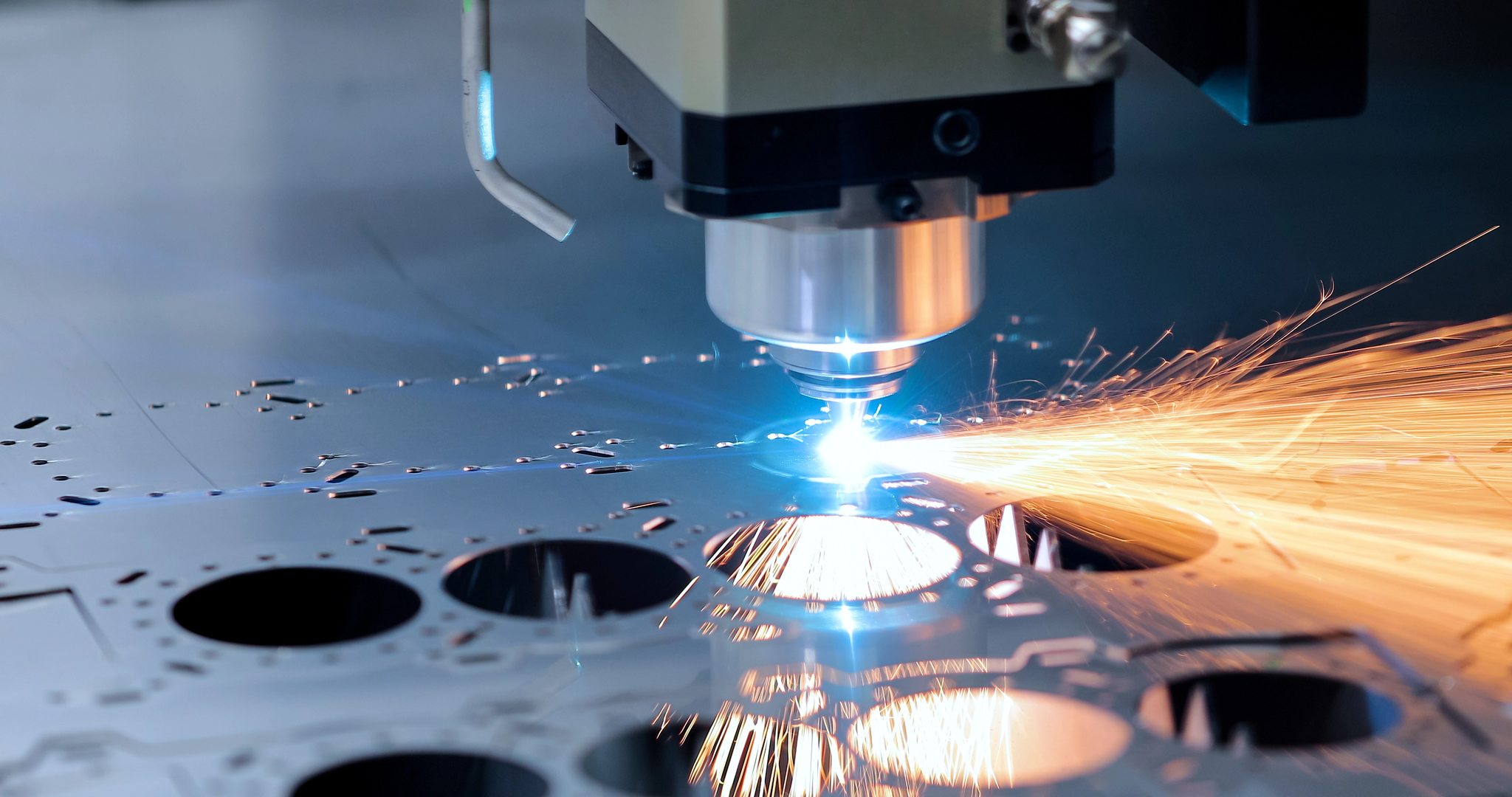 Laser cutting head machining sheet metal, blue arc and orange sparks from a CNC cutter.